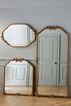 two mirrors sitting next to each other on top of a wooden floor in front of a gray wall