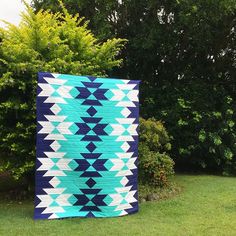 a blue and white quilt sitting on top of a lush green field