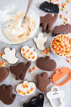 halloween cookies and candy are arranged on the table with icing, candies, and spoons