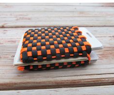 an orange and black checkered cell phone case sitting on top of a wooden table