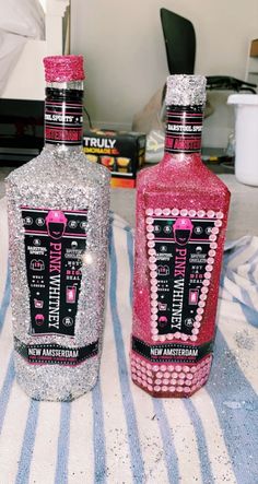 two bottles that are sitting next to each other on a tablecloth with silver and pink glitter