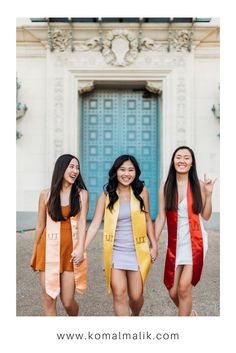 three young women are walking together in front of a building