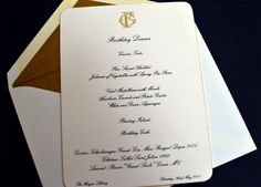 a white and gold wedding card on top of an envelope