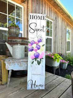 a wooden sign that says home sweet and has flowers painted on the side of it