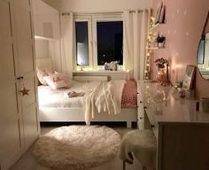 a bedroom with pink walls, white furniture and lights on the window sills