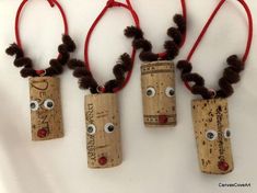 three wine corks with eyes and noses are hanging from red cords on a white surface