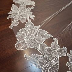 a white flower design on a clear plastic tablecloth with wood flooring in the background