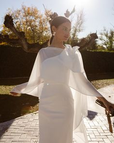 a woman in a white dress is holding an umbrella and standing on a brick walkway