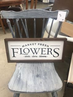 a sign that reads market fresh flowers sits on a wooden chair in a room filled with other furniture