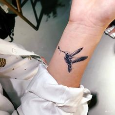 a small tattoo on the wrist of a woman with a hummingbird in it's beak