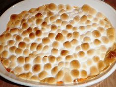 a white plate topped with a dessert covered in marshmallows on top of a wooden table