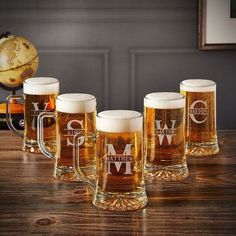 five beer mugs sitting on top of a wooden table next to a map and a globe