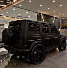 a black jeep is parked in front of a large glass building with lots of windows