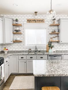 a kitchen with white cabinets and marble counter tops, along with wooden shelves above the sink