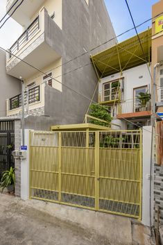 a yellow gate in front of a building with a balcony and balconies on the second floor