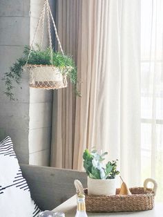 a white table topped with a bottle of wine and a basket filled with plants next to a window