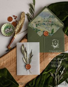 the wedding stationery is laid out on top of some green leafy papers and other items