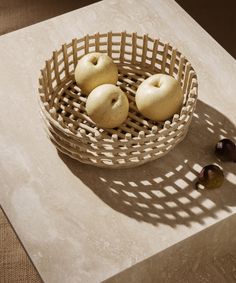 three apples are in a basket on a table with figurines next to it