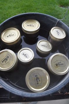 six empty beer cans sitting on top of a black tray with grass in the background