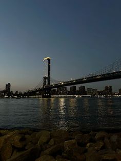 a large bridge spanning over a body of water with buildings in the background at night