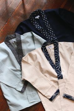 three different colored shirts sitting on top of a wooden floor