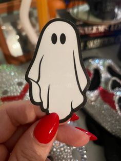 a hand holding up a sticker with a ghost on it