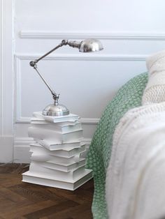 a stack of books sitting on top of a wooden floor next to a metal lamp