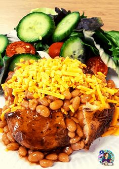 a white plate topped with beans and cucumbers next to a pile of vegetables