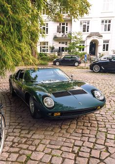 a green sports car parked in front of a white building