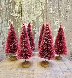 three small red trees are on top of a table