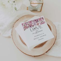 a table topped with a plate and napkins covered in flowers next to a candle