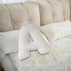 a white bed with pillows and a pillow shaped like the letter a