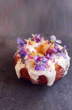 a donut with white icing and purple flowers on it sitting on a table