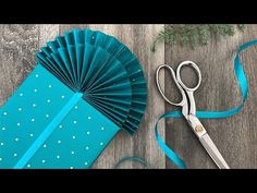 a pair of scissors sitting on top of a table next to a blue paper fan