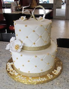 a white and gold wedding cake sitting on top of a table