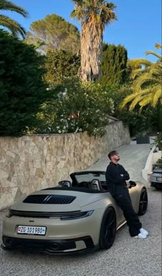 a man sitting on top of a silver sports car