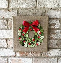 a christmas wreath made out of buttons on a burlocked canvas hanging on a brick wall