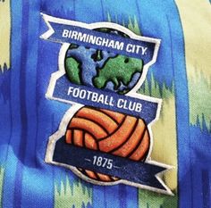 the birmingham city football club badge is shown on a blue and green tie - dye shirt