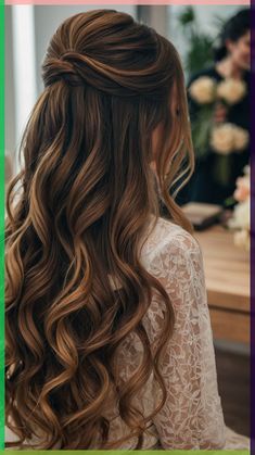 a woman with long, wavy hair is looking down at the camera and there are flowers in the background