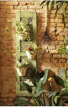 the interior of a brick building with potted plants and hanging birdhouses on the wall