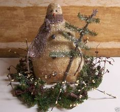 a snowman statue sitting on top of a table next to a wooden wall and tree