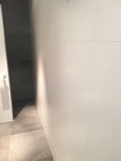 a bathroom with white walls and tile flooring next to a toilet paper dispenser