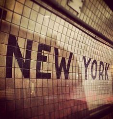 the words new york are written in black and white on a mosaic tile wall above a subway entrance