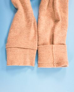 a pair of beige gloves on a blue background with the top part folded up to show the inside of the mittens