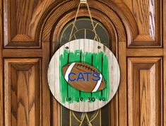 a wooden door with a sign that says cats on it and a football hanging from the front