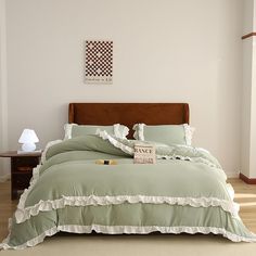 the bed is made with green and white ruffled bedspreads, pillows, and blankets