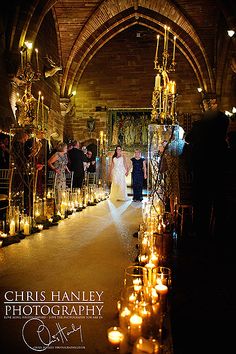 a bride and groom walking down the aisle at their wedding ceremony with candles in front of them