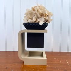 a vase filled with flowers sitting on top of a wooden table next to a white wall