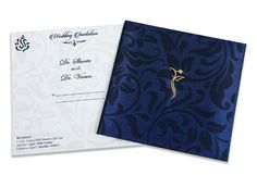 a blue and white wedding card with a gold brooch on the front, and an ornate design on the back