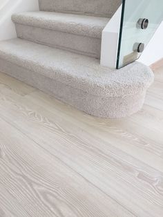 a white carpeted stair case with glass railing